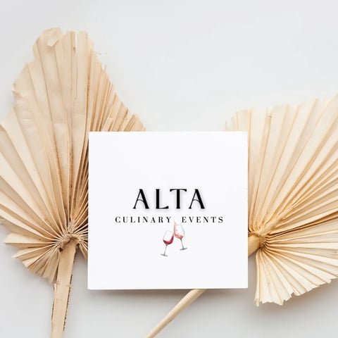 White card reading ALTA Culinary Events with wine glasses icon, surrounded by dried palm leaves on white background